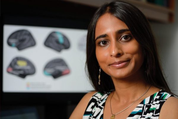 Archana Venkataraman poses in front of a blurry monitor.